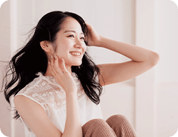 髪に手を添えて笑顔でくつろぐ女性