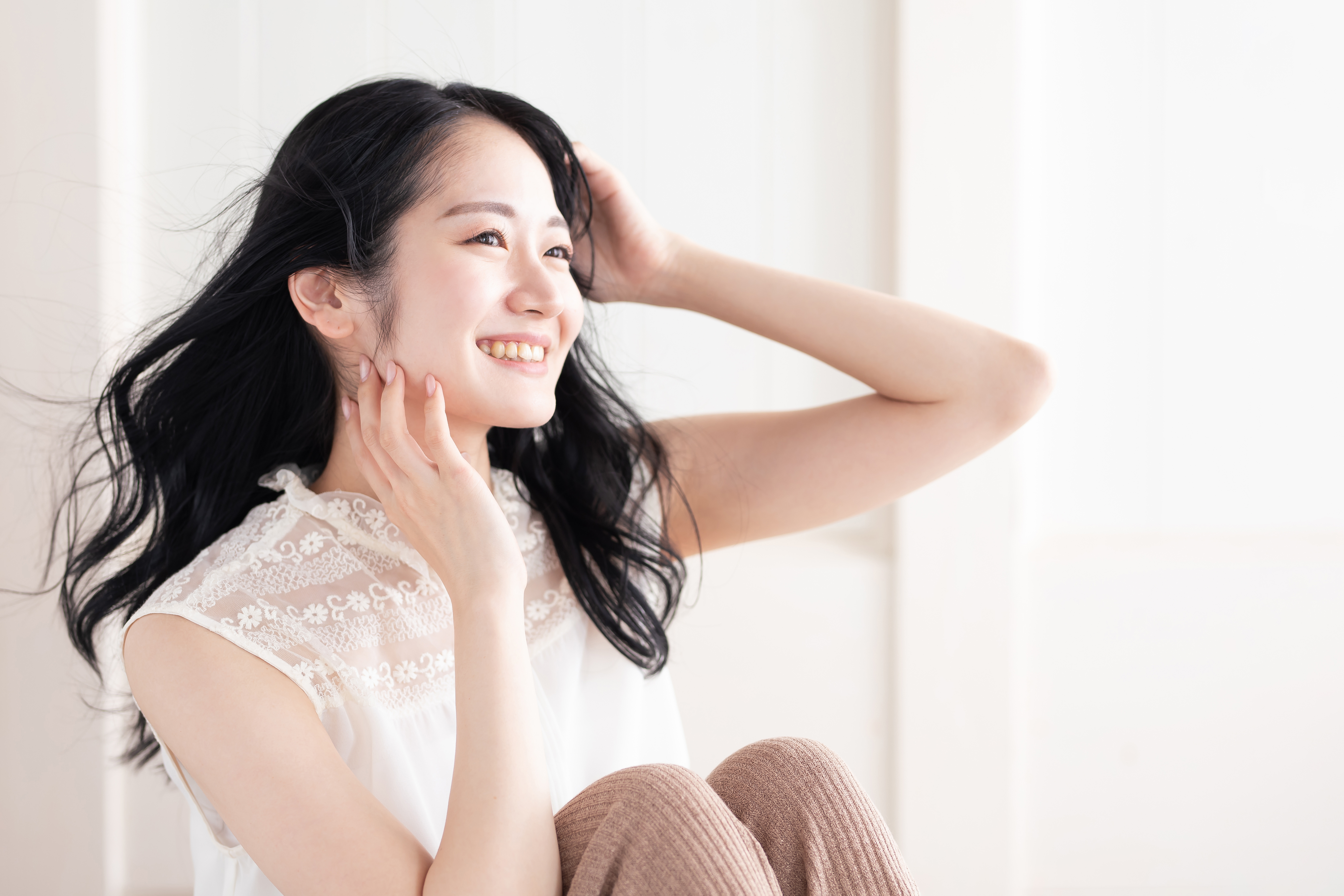 髪に手を添えて笑顔でくつろぐ女性