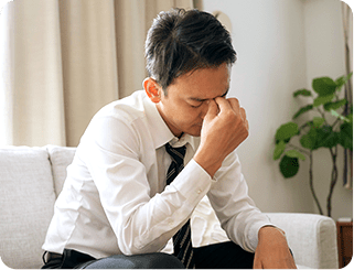 眉間を指で押さえて目の疲れを感じている男性
