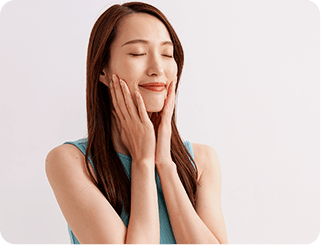 両手で頬を包み込み目を閉じて微笑む女性